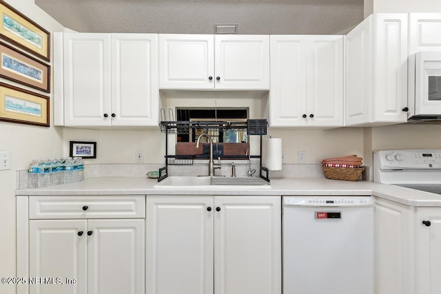 kitchen featuring light countertops, visible vents, white cabinetry, a sink, and white appliances