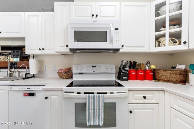 kitchen with light countertops, white appliances, a sink, and white cabinetry