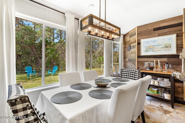 dining area with wood walls and an inviting chandelier