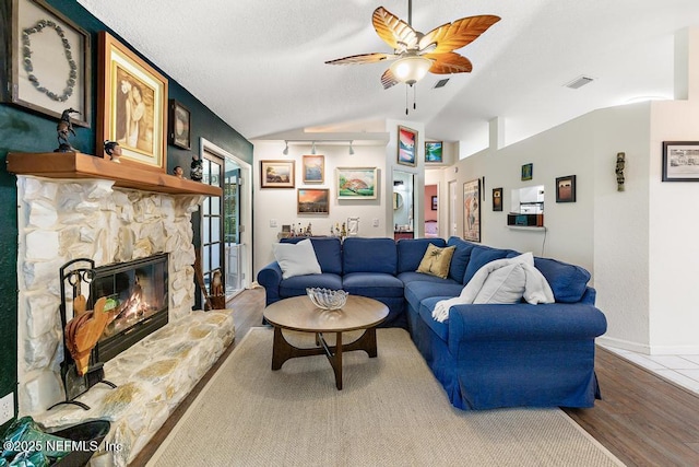 living area featuring baseboards, visible vents, lofted ceiling, wood finished floors, and a fireplace