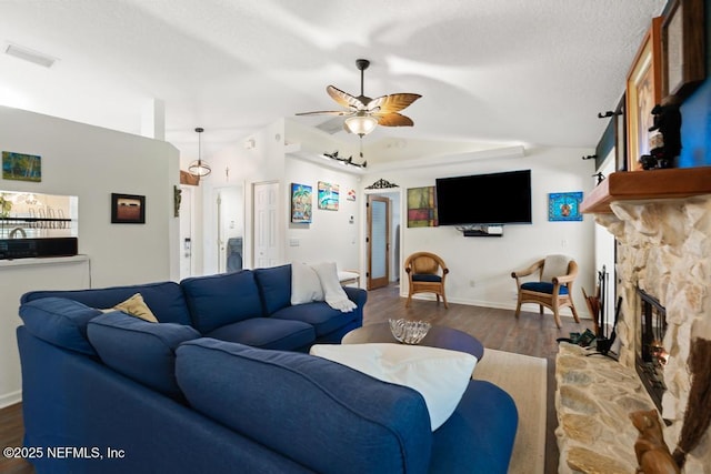 living room with ceiling fan, a textured ceiling, a fireplace, wood finished floors, and visible vents