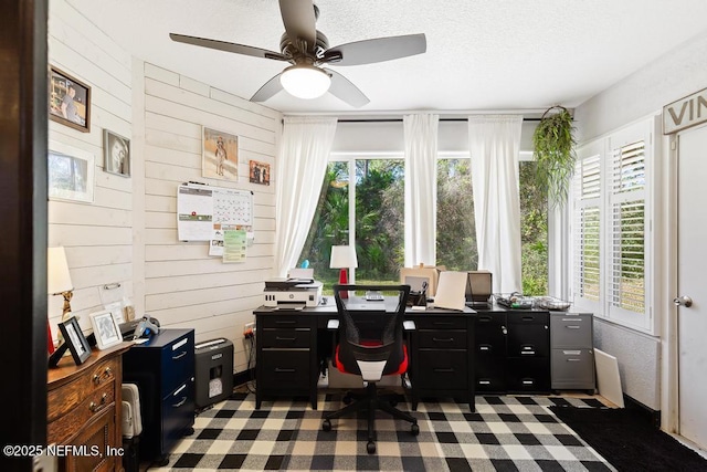 office space with ceiling fan, wood walls, and a textured ceiling