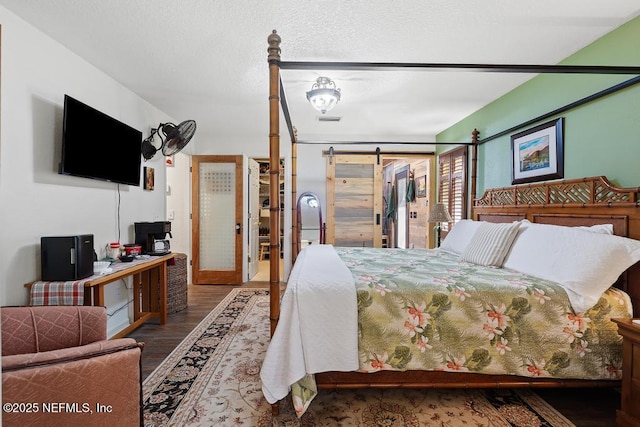 bedroom featuring a textured ceiling, a barn door, and wood finished floors