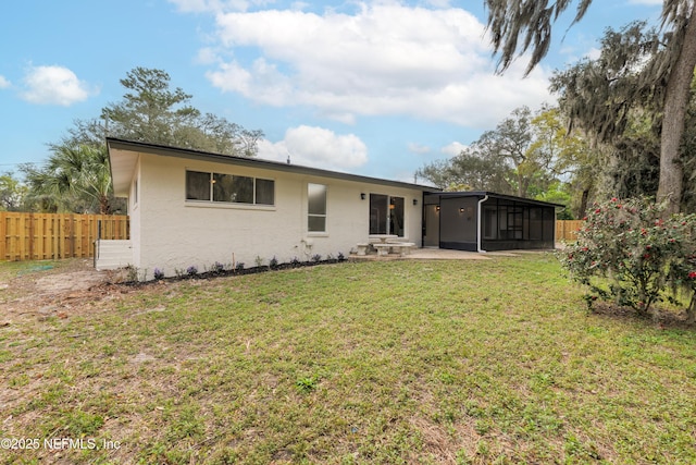 rear view of property featuring a lawn, a patio, a sunroom, fence, and stucco siding