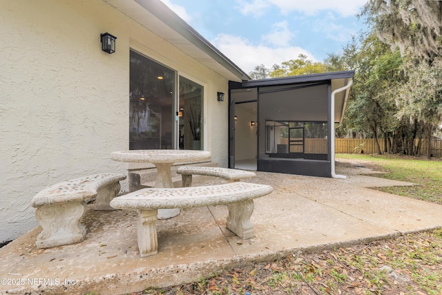 entrance to property featuring stucco siding, fence, and a patio