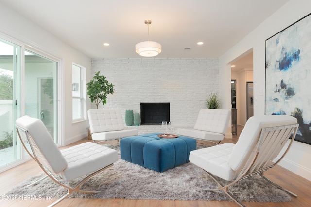 living room featuring a brick fireplace, baseboards, and wood finished floors