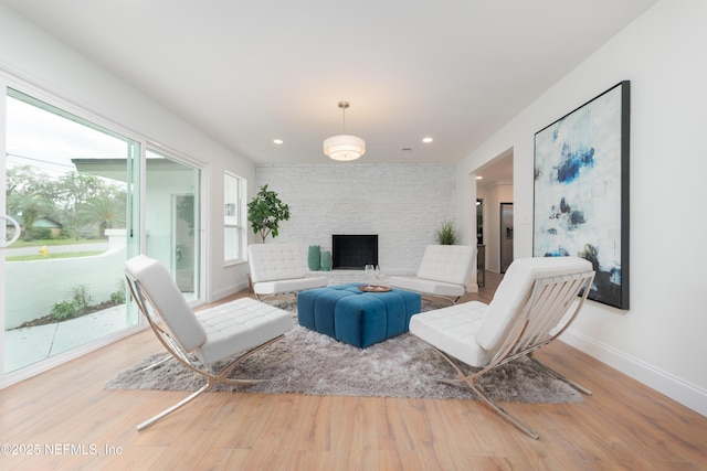 living room with recessed lighting, a brick fireplace, baseboards, and wood finished floors