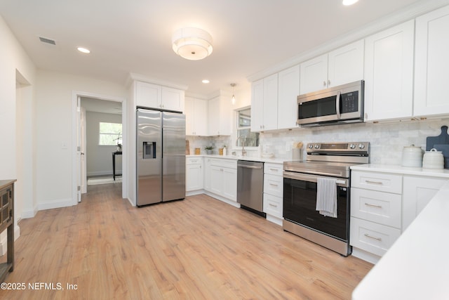 kitchen with light countertops, appliances with stainless steel finishes, white cabinetry, and tasteful backsplash