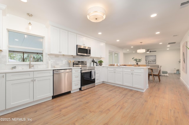 kitchen with a peninsula, appliances with stainless steel finishes, visible vents, and tasteful backsplash