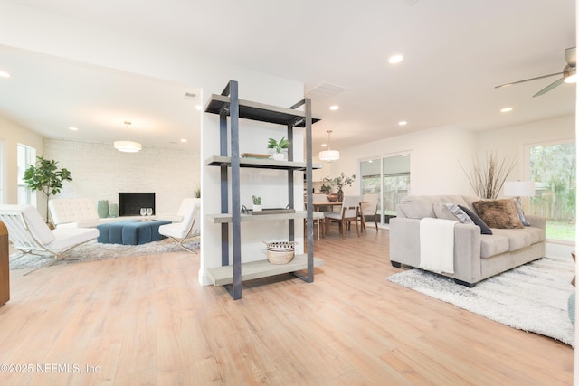 living room featuring light wood finished floors, visible vents, ceiling fan, brick wall, and recessed lighting