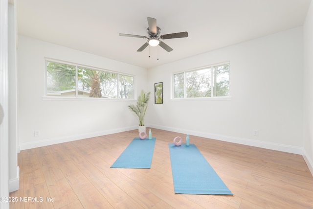 exercise room featuring light wood-style floors, a healthy amount of sunlight, and baseboards