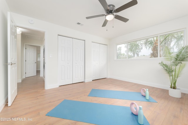 exercise room featuring light wood-type flooring, baseboards, visible vents, and attic access