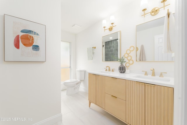 bathroom with baseboards, a sink, toilet, and double vanity