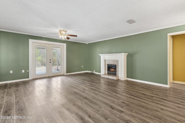 unfurnished living room featuring french doors, visible vents, ornamental molding, wood finished floors, and a tile fireplace