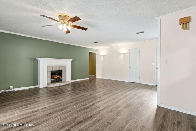 unfurnished living room featuring ceiling fan, a tiled fireplace, wood finished floors, and crown molding