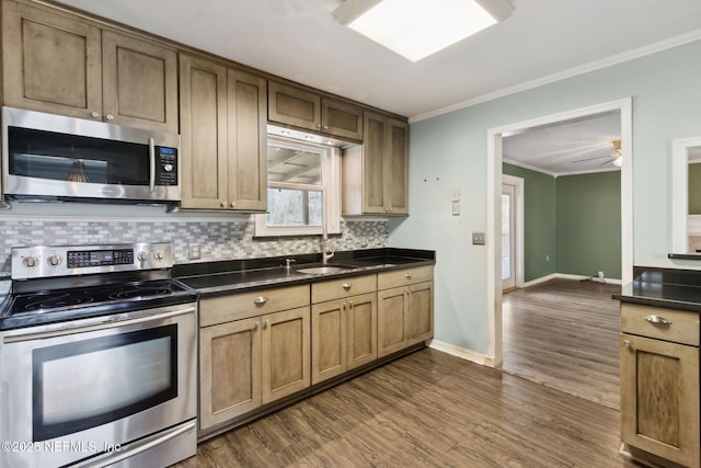 kitchen with stainless steel appliances, dark countertops, decorative backsplash, ornamental molding, and a sink