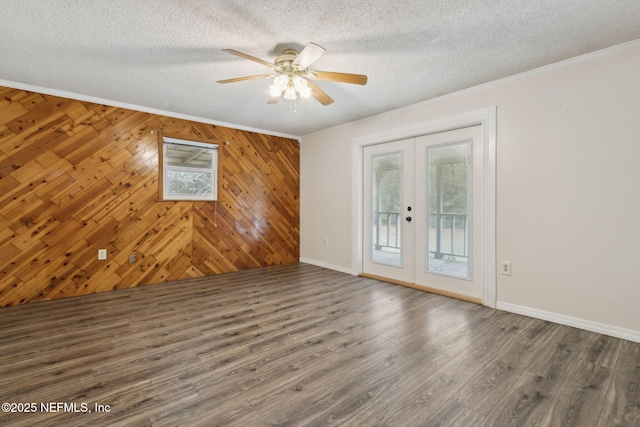 empty room featuring a textured ceiling, ornamental molding, wood finished floors, and french doors