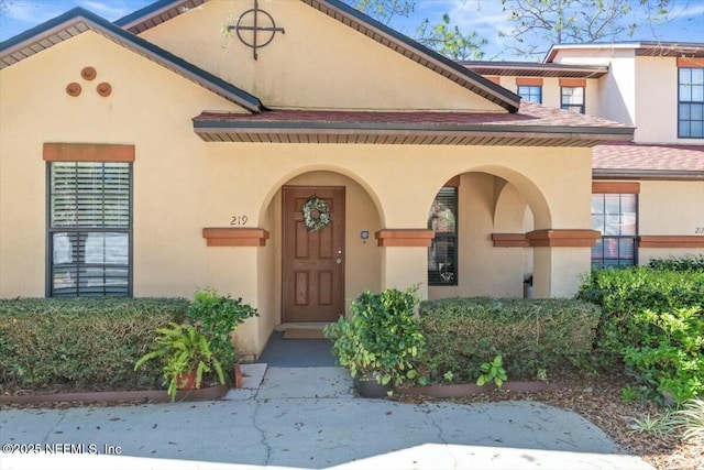 property entrance featuring stucco siding and roof with shingles