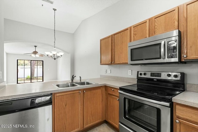 kitchen with lofted ceiling, a sink, light countertops, appliances with stainless steel finishes, and pendant lighting