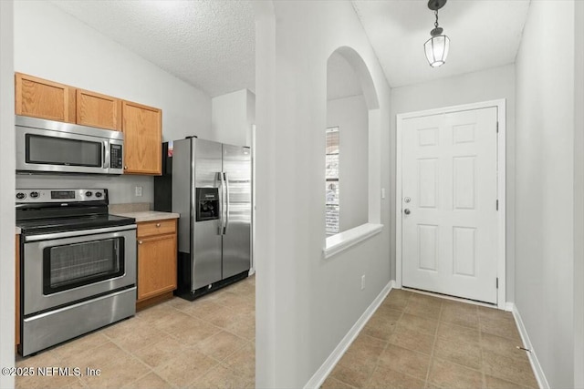 kitchen with baseboards, vaulted ceiling, light countertops, appliances with stainless steel finishes, and pendant lighting