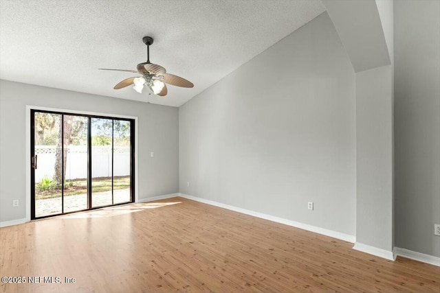 empty room featuring ceiling fan, baseboards, lofted ceiling, wood finished floors, and a textured ceiling