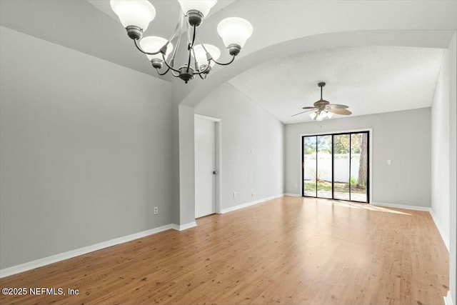 unfurnished room with light wood-style flooring, ceiling fan with notable chandelier, arched walkways, and baseboards