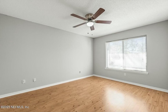 empty room with a textured ceiling, baseboards, and wood finished floors