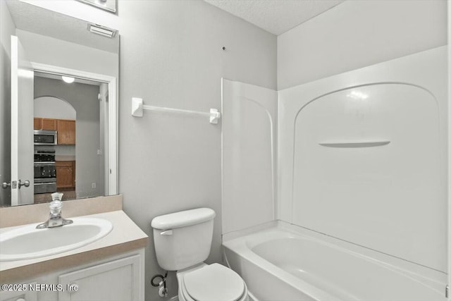 full bath featuring toilet, a textured ceiling, vanity, and bathtub / shower combination