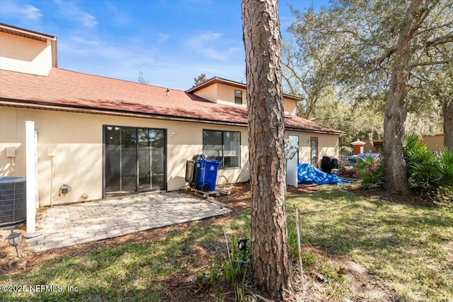 rear view of house featuring stucco siding, a patio, a lawn, and central AC unit