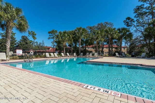 community pool with a patio area and fence