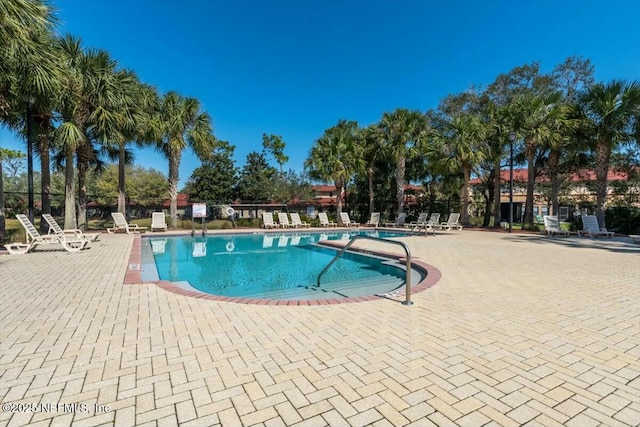 pool with a patio area and fence