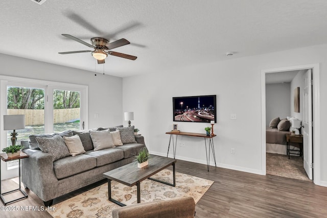 living area featuring ceiling fan, wood finished floors, baseboards, and a textured ceiling