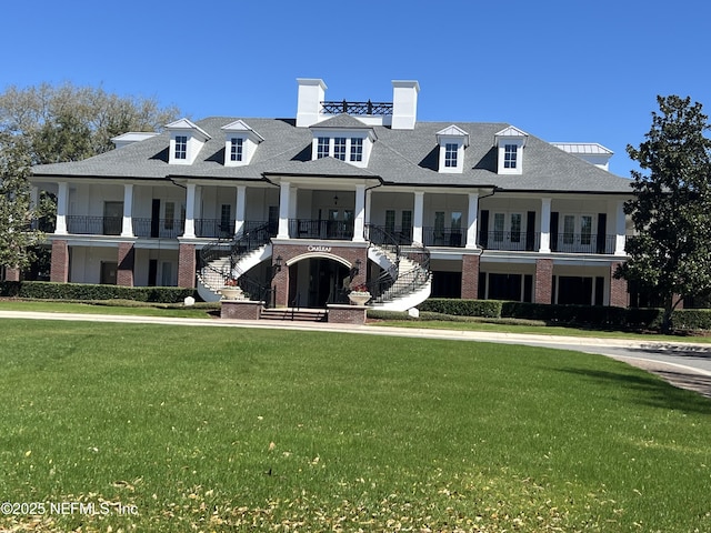 view of front of house featuring brick siding, stairway, and a front lawn