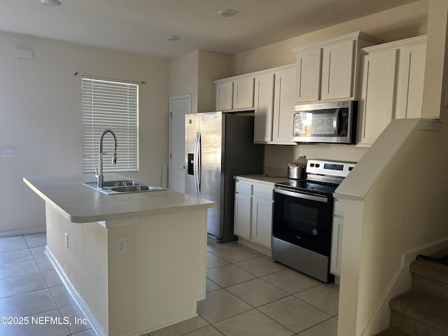 kitchen with light tile patterned floors, a kitchen island with sink, stainless steel appliances, light countertops, and a sink