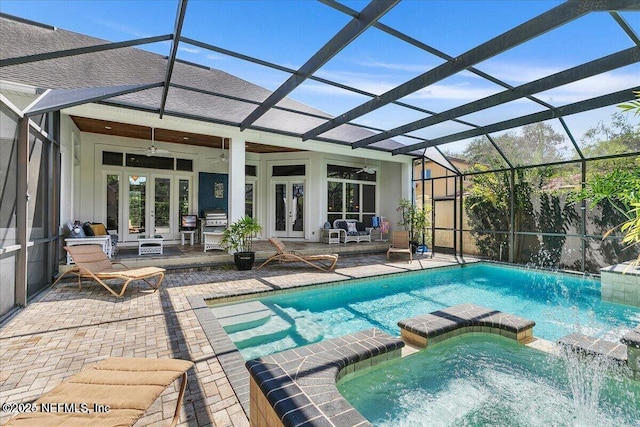 view of pool with glass enclosure, a ceiling fan, a pool with connected hot tub, french doors, and a patio area