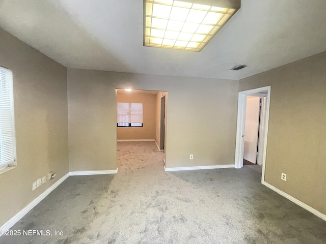 carpeted spare room with visible vents and baseboards