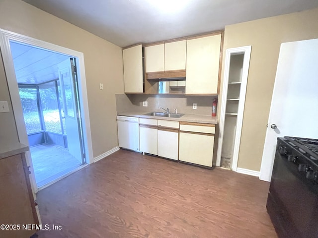 kitchen featuring black range with gas cooktop, white dishwasher, a sink, light countertops, and tasteful backsplash