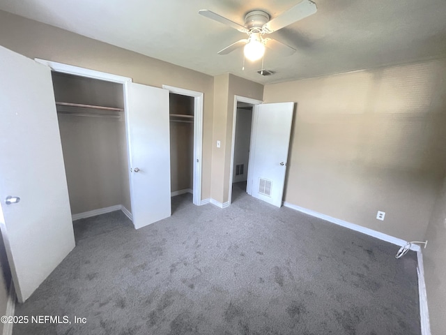 unfurnished bedroom with baseboards, visible vents, multiple closets, and carpet flooring