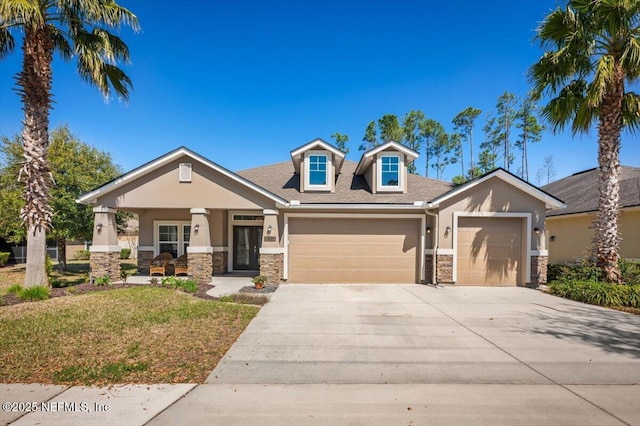 view of front of house with a front yard, stucco siding, driveway, stone siding, and an attached garage