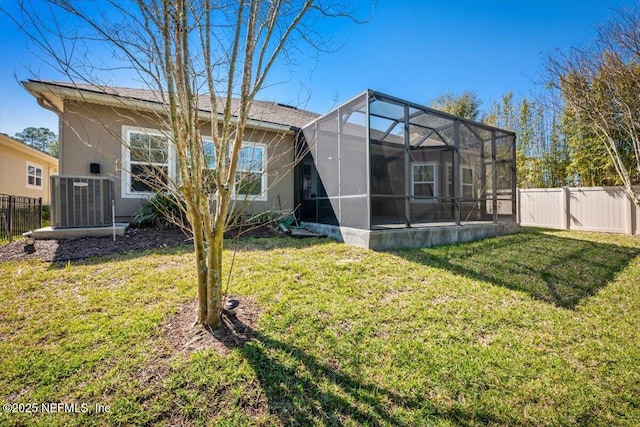 back of property featuring a lanai, central air condition unit, a yard, and a fenced backyard