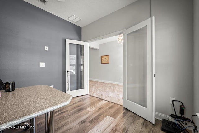 interior space featuring wood finished floors, french doors, visible vents, and baseboards