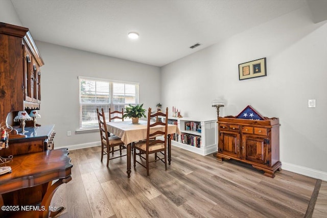 dining area featuring light wood-style floors, visible vents, and baseboards