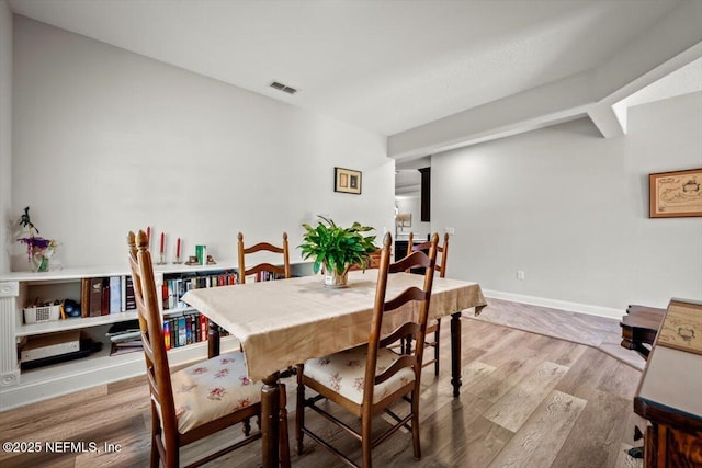 dining space featuring visible vents, light wood-style flooring, and baseboards