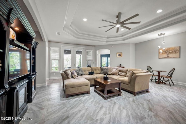 living area with a ceiling fan, a tray ceiling, arched walkways, french doors, and crown molding