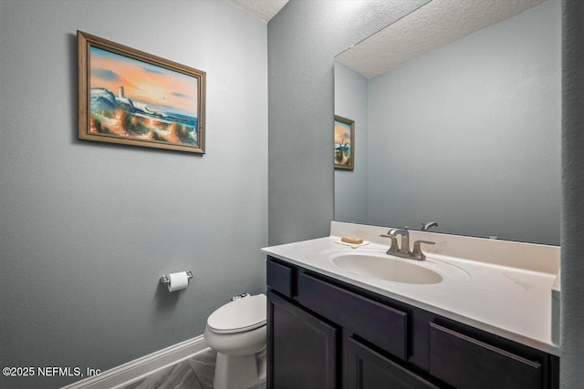 half bathroom with vanity, toilet, and baseboards