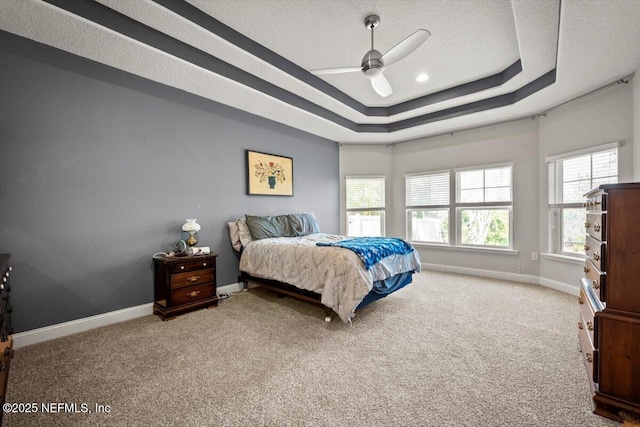 carpeted bedroom with a tray ceiling, baseboards, a textured ceiling, and ceiling fan