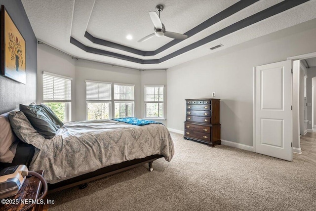 carpeted bedroom featuring visible vents, ceiling fan, baseboards, a textured ceiling, and a raised ceiling