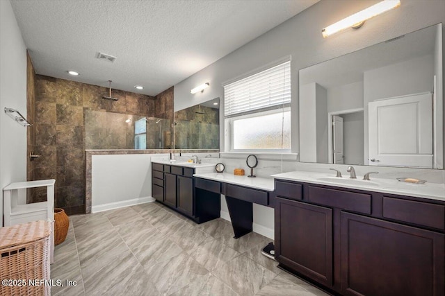 full bathroom with vanity, a textured ceiling, visible vents, and walk in shower