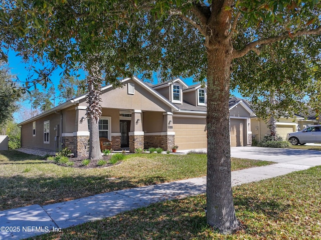 view of front of home with concrete driveway, stone siding, a front yard, and stucco siding