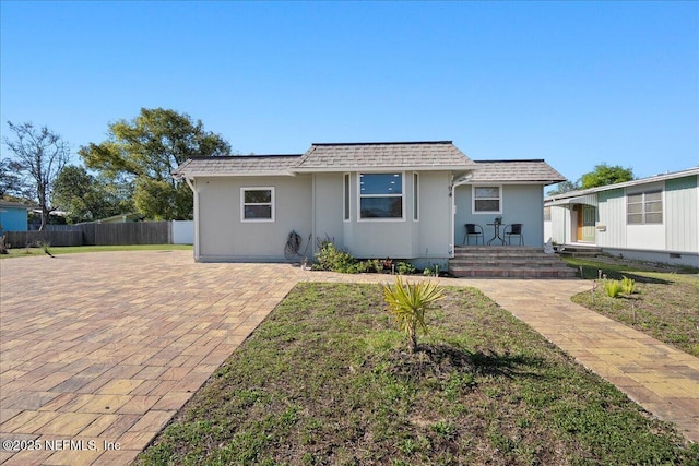 view of front of house with fence, a front lawn, and a shingled roof